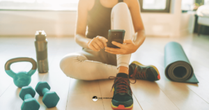 imagem de uma mulher usando o celular que tem um aplicativo fitness online